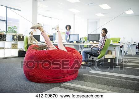 Businesswoman playing in beanbag chair in office View Large Photo Image Stock Image - Businesswoman playing in beanbag chair in office. Fotosearch