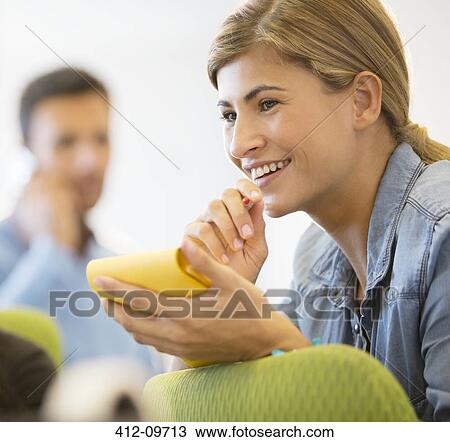 Stock Image - Businesswoman taking notes in office. Fotosearch