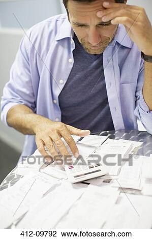 Stock Image - Frustrated man paying bills. Fotosearch