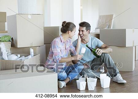 Picture - Couple drinking champagne and eating Chinese food on floor in new house. Fotosearch