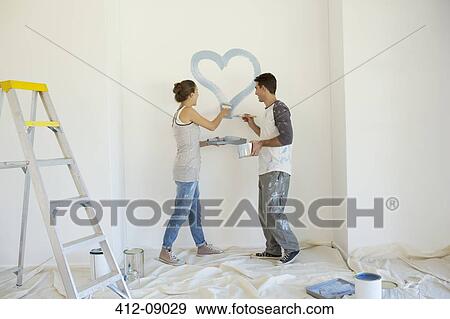 Couple painting blue heart on wall View Large Photo Image Stock Photo - Couple painting blue heart on wall. Fotosearch