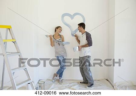 Couple painting blue heart on wall View Large Photo Image Stock Photograph - Couple painting blue heart on wall. Fotosearch