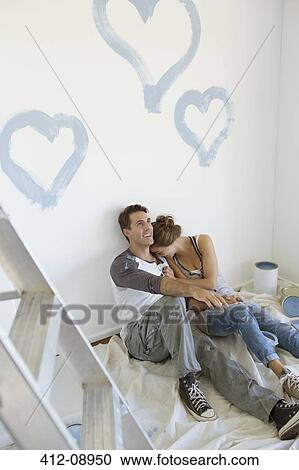 Stock Image - Couple painting blue hearts on wall. Fotosearch