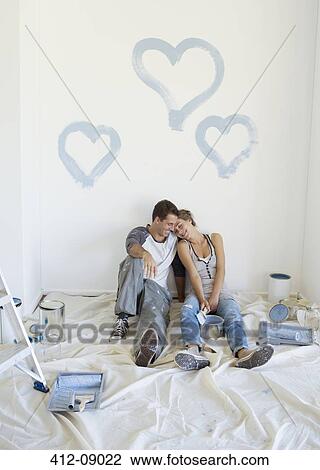 Stock Image - Couple painting blue hearts on wall. Fotosearch