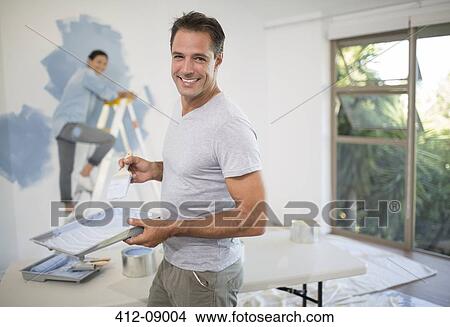 Picture - Couple painting wall blue. Fotosearch