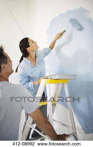 Stock Image - Couple painting wall blue. Fotosearch