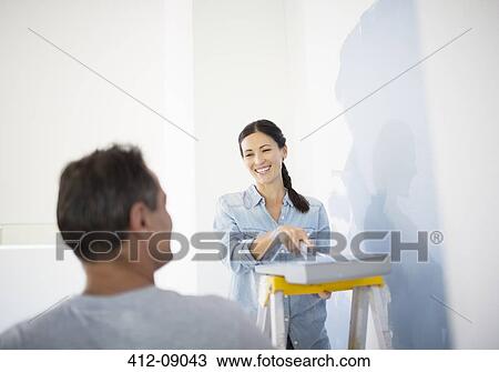 Stock Image - Couple painting wall blue. Fotosearch