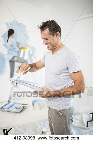 Stock Photo - Couple painting wall blue. Fotosearch