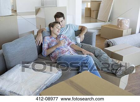 Couple relaxing on sofa in new house View Large Photo Image Stock Photo - Couple relaxing on sofa in new house. Fotosearch
