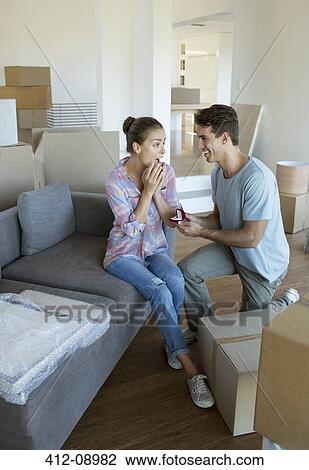 Stock Image - Man proposing to girlfriend in new house. Fotosearch