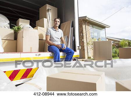 Picture - Man sitting in moving truck in driveway. Fotosearch