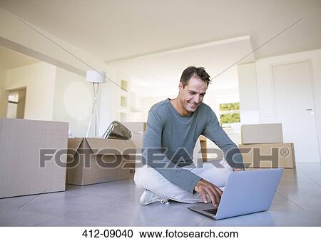 Man using laptop on floor among cardboard boxes View Large Photo Image Stock Image - Man using laptop on floor among cardboard boxes. Fotosearch