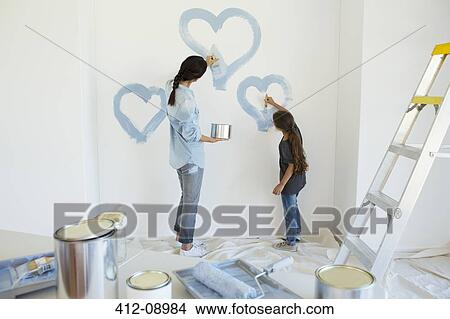 Picture - Mother and daughter painting blue hearts on wall in new house. Fotosearch