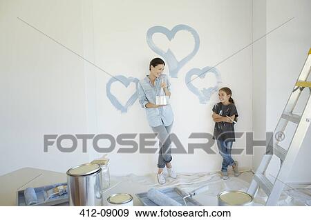 Mother and daughter painting blue hearts on wall View Large Photo Image Stock Photo - Mother and daughter painting blue hearts on wall. Fotosearch