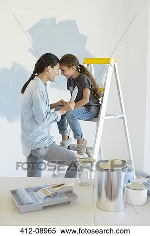 Stock Photography - Mother and daughter painting wall blue. Fotosearch