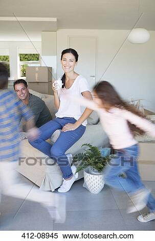 Parents watching children run around living room in new house View Large Photo Image Stock Photography - Parents watching children run around living room in new house. Fotosearch