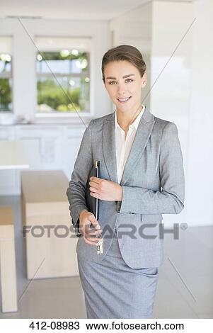 Stock Image - Portrait of confident realtor holding house keys. Fotosearch