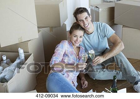 Picture - Portrait of couple enjoying champagne among cardboard boxes. Fotosearch
