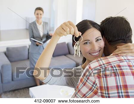 Stock Photo - Portrait of happy couple hugging with house keys. Fotosearch