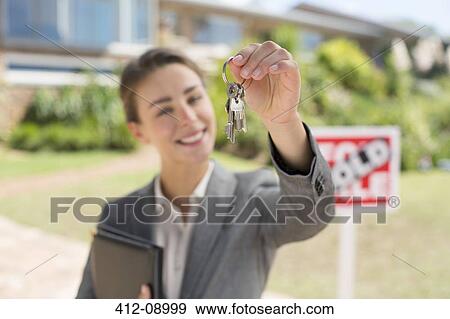 Portrait of realtor holding house keys in front of house View Large Photo Image Stock Photo - Portrait of realtor holding house keys in front of house. Fotosearch