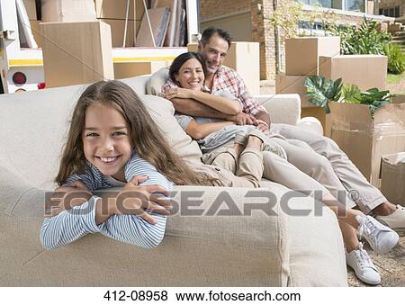Stock Photo - Portrait of smiling family on sofa in driveway near moving van. Fotosearch