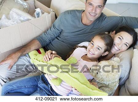 Stock Image - Portrait of smiling family with stuffed animals on sofa. Fotosearch