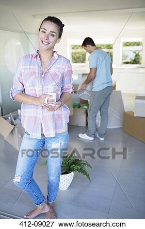 Stock Photo - Portrait of woman holding coffee cup among cardboard boxes. Fotosearch