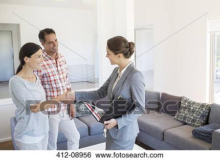 Realtor and couple handshaking in living room View Large Photo Image Stock Photograph - Realtor and couple handshaking in living room. Fotosearch
