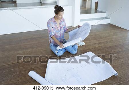 Woman examining blueprints on floor in empty living room View Large Photo Image Stock Photography - Woman examining blueprints on floor in empty living room. Fotosearch