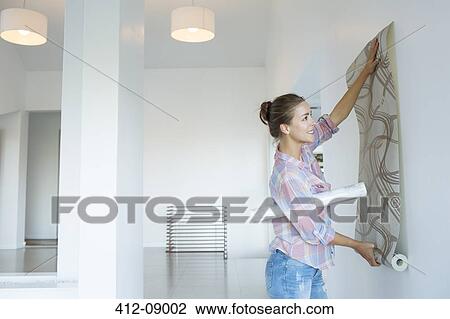 Woman hanging wallpaper in new house View Large Photo Image Stock Image - Woman hanging wallpaper in new house. Fotosearch