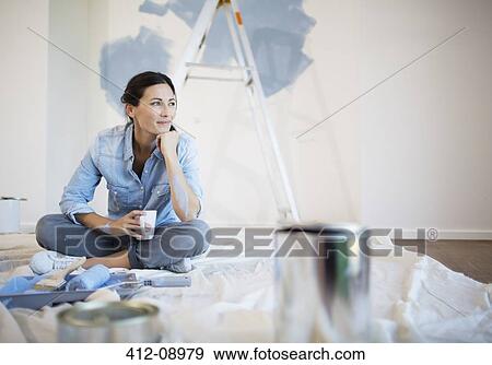 Stock Photo - Woman relaxing with coffee among painting supplies. Fotosearch