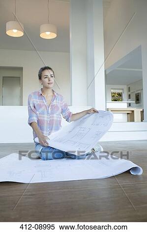 Woman with blueprints on floor in new house View Large Photo Image Stock Photography - Woman with blueprints on floor in new house. Fotosearch