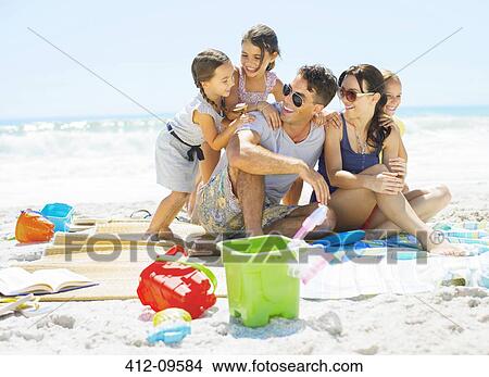 Picture - Family hugging on blanket at beach. Fotosearch