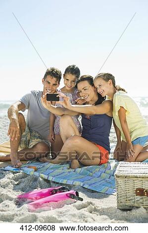 Stock Photo - Family taking self-portrait with camera phone at beach. Fotosearch