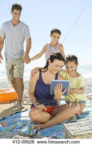 Family using digital tablet on beach View Large Photo Image Stock Photo - Family using digital tablet on beach. Fotosearch