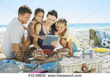 Stock Photography - Family using digital tablet on beach. Fotosearch
