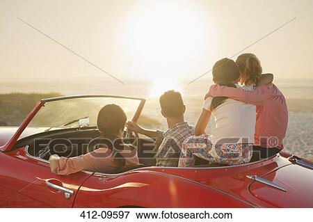 Family watching sunset over ocean from convertible on beach View Large Photo Image Stock Photo - Family watching sunset over ocean from convertible on beach. Fotosearch