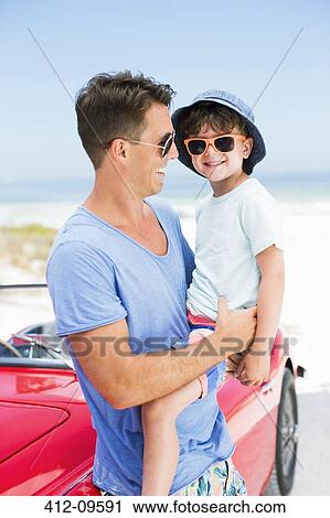 Father and son smiling on beach next to convertible View Large Photo Image Stock Image - Father and son smiling on beach next to convertible. Fotosearch