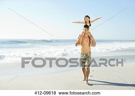 Father carrying daughter on shoulders at beach View Large Photo Image Stock Photo - Father carrying daughter on shoulders at beach. Fotosearch