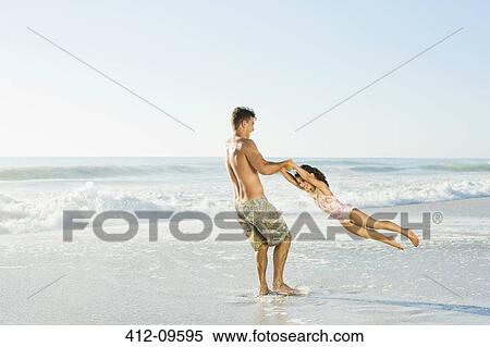 Father swinging daughter in surf at beach View Large Photo Image Stock Photography - Father swinging daughter in surf at beach. Fotosearch