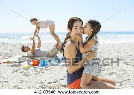 Girl kissing mother's cheek at beach View Large Photo Image Stock Image - Girl kissing mother's cheek at beach. Fotosearch