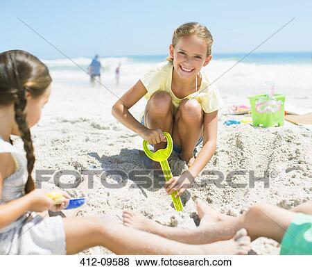 Girls digging in sand on beach View Large Photo Image Stock Photo - Girls digging in sand on beach. Fotosearch