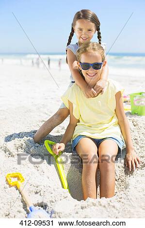 Stock Image - Girls playing in sand at beach. Fotosearch