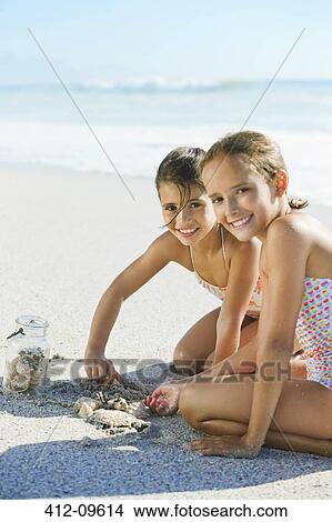 Girls playing in sand on beach View Large Photo Image Picture - Girls playing in sand on beach. Fotosearch