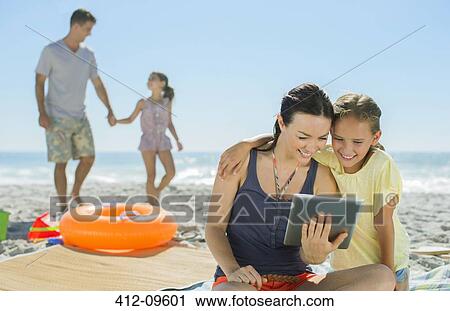 Mother and daughter using digital tablet on beach View Large Photo Image Stock Image - Mother and daughter using digital tablet on beach. Fotosearch