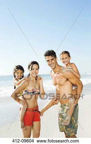 Parents carrying daughters piggyback on beach View Large Photo Image Picture - Parents carrying daughters piggyback on beach. Fotosearch