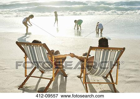 Parents watching children play on beach View Large Photo Image Stock Photo - Parents watching children play on beach. Fotosearch