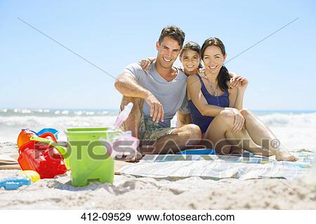Portrait of smiling family sitting on beach View Large Photo Image Stock Photo - Portrait of smiling family sitting on beach. Fotosearch
