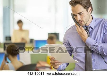 Businessman reading papers in office View Large Photo Image Stock Image - Businessman reading papers in office. Fotosearch
