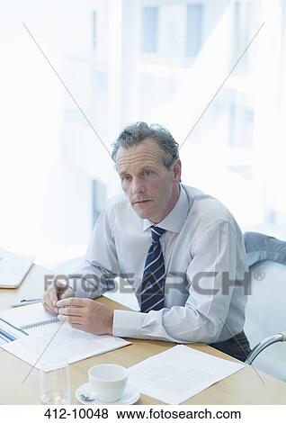 Stock Photo - Businessman sitting at desk in office. Fotosearch